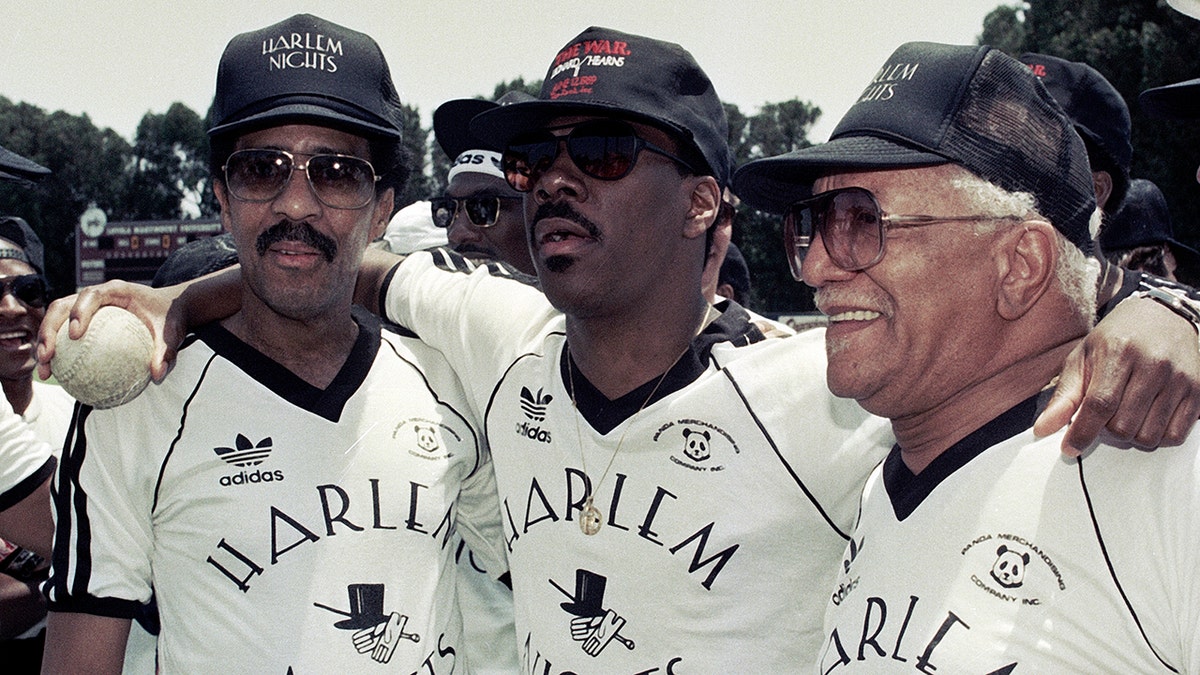 Richard Pryor, Eddie Murphy and Redd Foxx all in Harlem Nights jerseys and caps pose for a photo