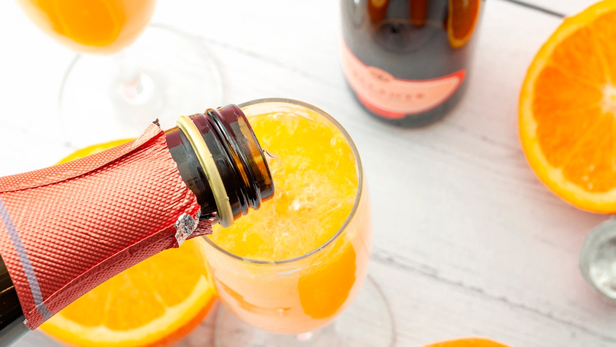 Pouring champagne in mimosa glass