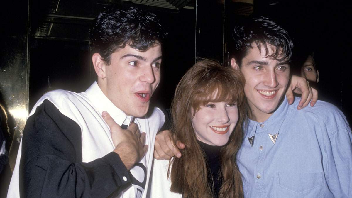 Tiffany smiling and posing in between two members of New Kids On The Block