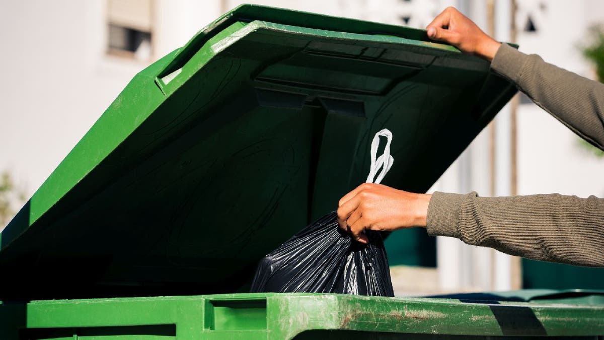 Man takes out garbage and puts in trash bin